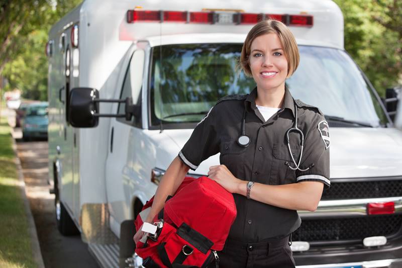 Portrait of a happy paramedica carrying a portable oxygen unit